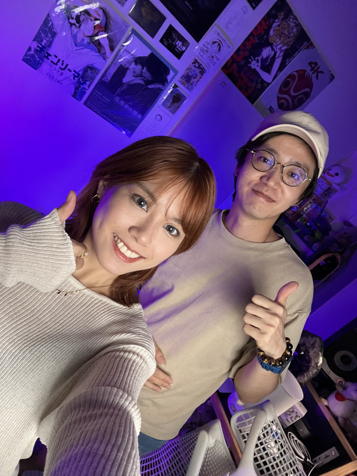 紫色燈光的工作室裡兩個人靠在一起合照,其中一人比出大拇指。
